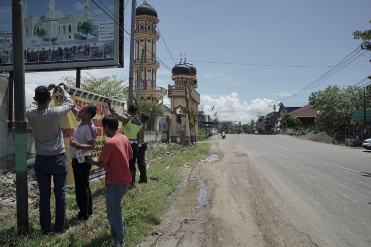 Personel Sat Lantas Polres Lhokseumawe memasang spanduk himbauan di empat titik kawasan rawan kecelakaan lalu lintas