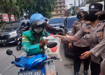 Personil Polrestabes Medan memberikan sembako berupa beras dan gula, kepada masyarakat yang kurang mampu