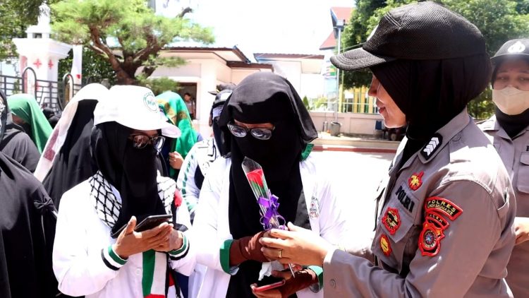 Polisi Wanita (Polwan) Polres Lhokseumawe yang ikut mengamankan demo tersebut sukses mencairkan dan membuat adem suasana dengan membagikan bunga kepada peserta aksi