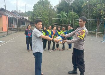 Bhabinkamtibmas Kelurahan Leuwiliang AIPTU Anas menyerahkan bola voli kepada warga di Kampung Babakan Rengrang Kelurahan Leuwiliang Kecamatan Kawalu