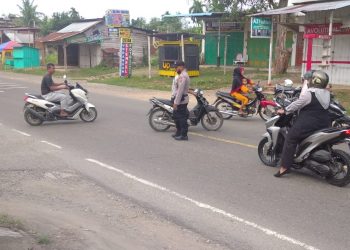 Personel Polsek Muara Batu melakukan pengaturan lalulintas di Jalan Medan - Banda Aceh tepatnya di Simpang Pendidikan