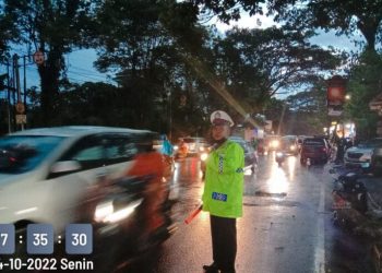 Sat Lantas Polresta Manado melaksanakan pengaturan arus lalu lintas di jalan Walanda Maramis, lengkap dengan menggunakan jas hujan