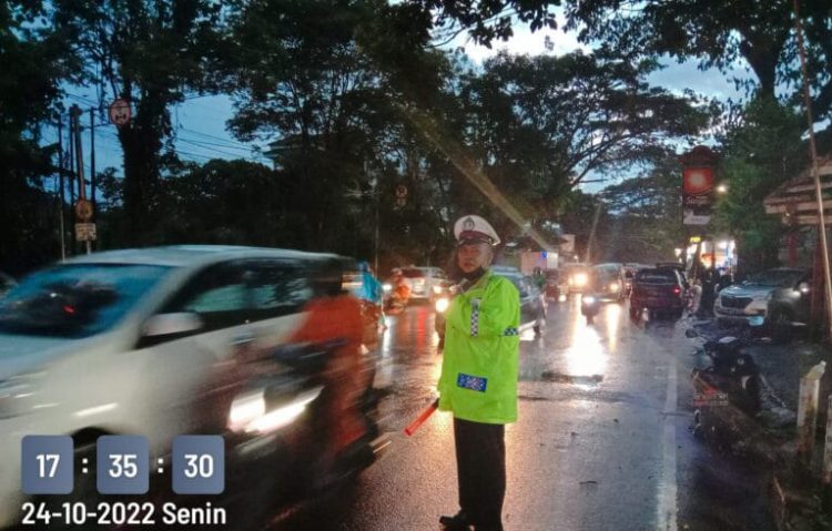 Sat Lantas Polresta Manado melaksanakan pengaturan arus lalu lintas di jalan Walanda Maramis, lengkap dengan menggunakan jas hujan
