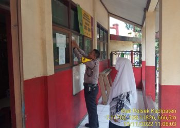 Bhabinkamtibmas Desa Cibahayu BRIPKA Maksun memasang stiker kontak person di SDN 1 Cibahayu Kecamatan Kadilaten