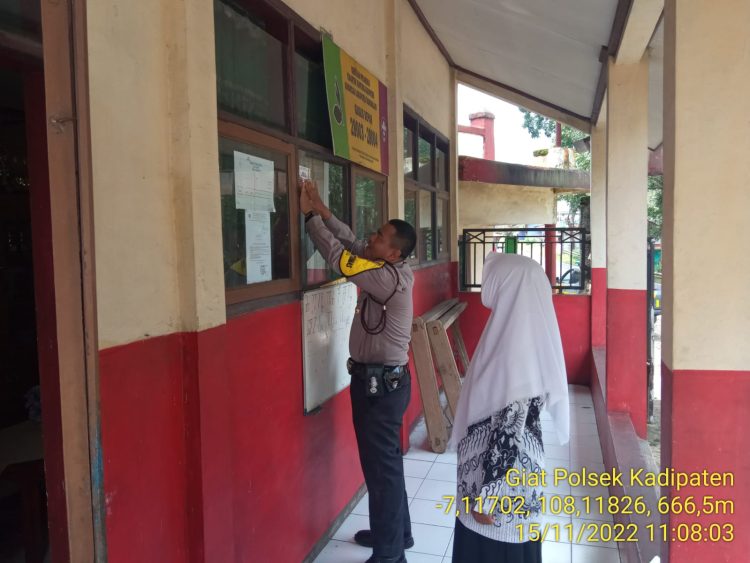 Bhabinkamtibmas Desa Cibahayu BRIPKA Maksun memasang stiker kontak person di SDN 1 Cibahayu Kecamatan Kadilaten