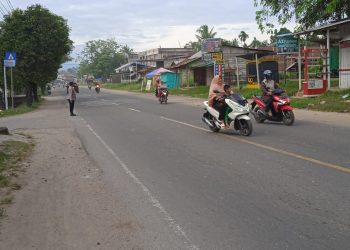 Personel Polsek Muara Batu membantu siswa menyeberang jalan pada kegiatan strong poin atau pengaturan lalulintas di Jalan Medan - Banda Aceh