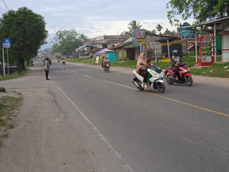 Personel Polsek Muara Batu membantu siswa menyeberang jalan pada kegiatan strong poin atau pengaturan lalulintas di Jalan Medan - Banda Aceh