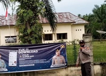 Personel Polsek Syamtalira Bayu memasang spanduk "Yuk!!! Download Polri Super Apps" di tempat publik