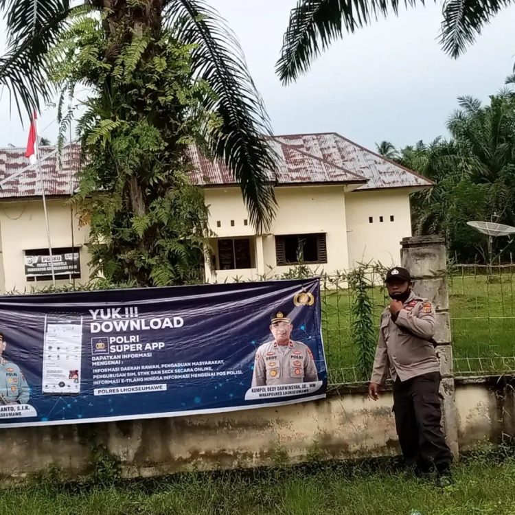 Personel Polsek Syamtalira Bayu memasang spanduk "Yuk!!! Download Polri Super Apps" di tempat publik