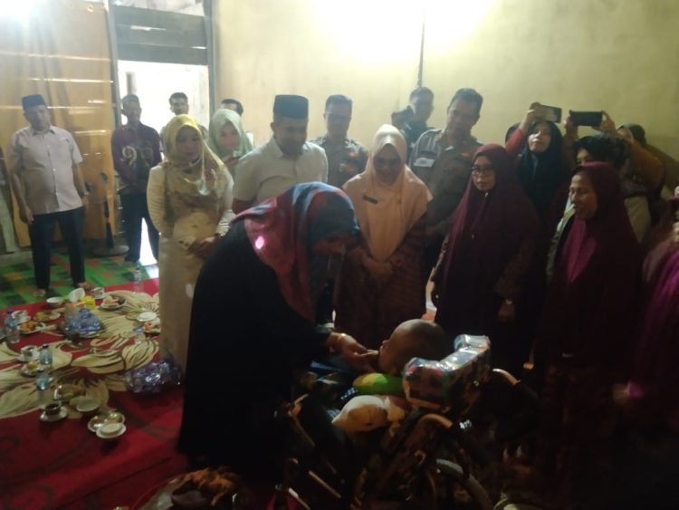 Penjabat (Pj) Bupati Nagan Raya, Fitriany Farhas, S.Sos, M.Si menepung tawari (peusijuk) Diki Fadillah (7), seorang anak penderita hydrosefalus