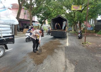Polisi dari Polsek Kalimanah Polres Purbalingga bersama warga menutup tumpahan minyak goreng yang tercecer di jalan raya Sukarno Hatta, Kelurahan Kalikabong