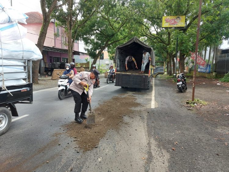 Polisi dari Polsek Kalimanah Polres Purbalingga bersama warga menutup tumpahan minyak goreng yang tercecer di jalan raya Sukarno Hatta, Kelurahan Kalikabong