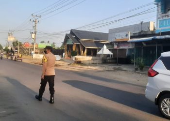 Personel Polsek Dewantara memberikan pelayanan kepada pengguna jalan raya di pagi hari di Simpang IV Keude Krueng Geukueh, Dewantara, Aceh Utara