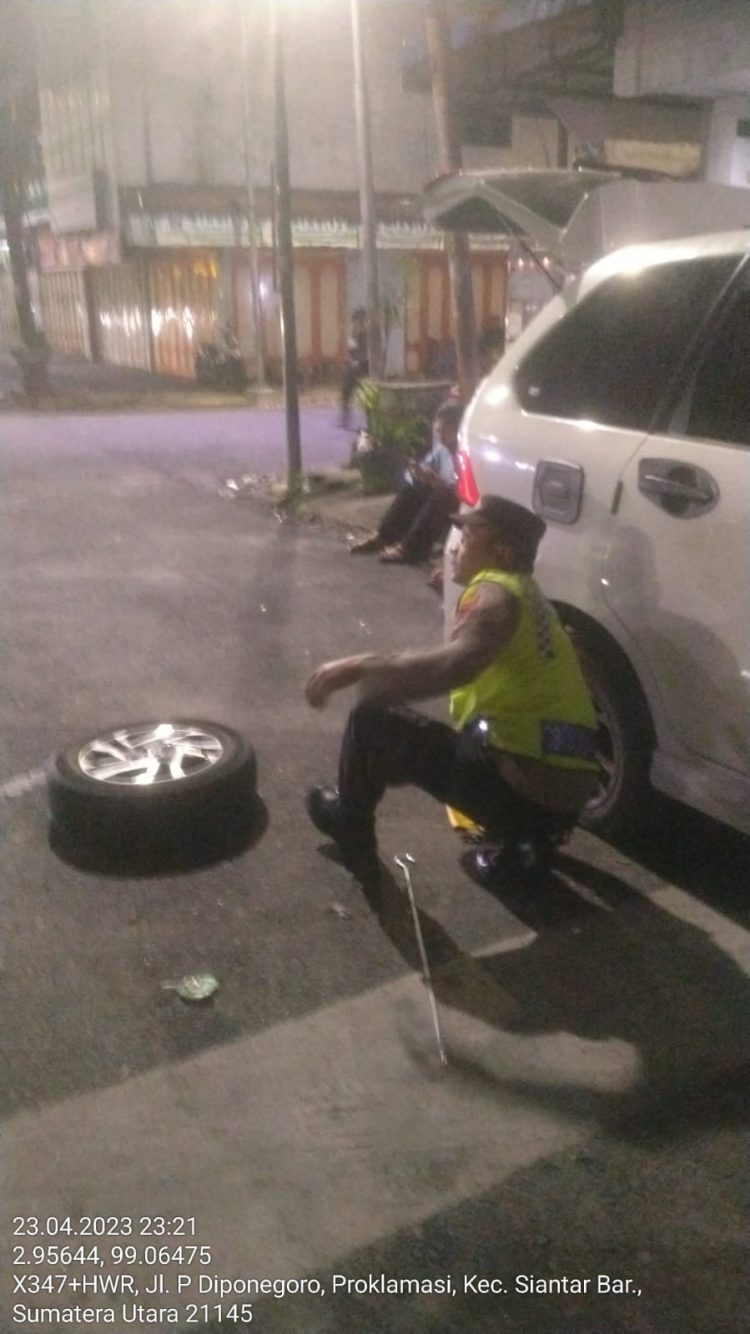 Personel Polsek Siantar Barat, hadir mengayomi tulus melayani masyarakat pemudik yang mengalami kempes ban mobil didepan toko roti ganda, Jalan Sutomo, Kelurahan Dwikora, Kecamatan Siantar barat, Kota Siantar, Minggu (23/04/2023)