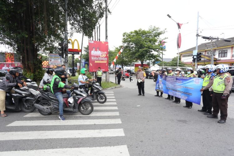 Personel lantas membentangkan spanduk berisi himbauan kepada pengguna jalan di Persimpangan Jalan Pelangi Medan pada Ops Patuh Toba 2023, Senin (10/7/2023). (Foto Dok/ Polda Sumut)