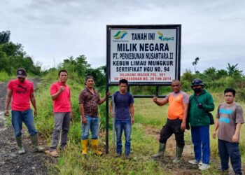 PLANG HGU : Karyawan PTPN2 Kebun Limau Mungkur berfose di jalan masuk menuju areal yang akan dibersihkan dan terdapat plang HGU milik PTPN2, baru-baru ini. (Foto.Dok/PTPN2).