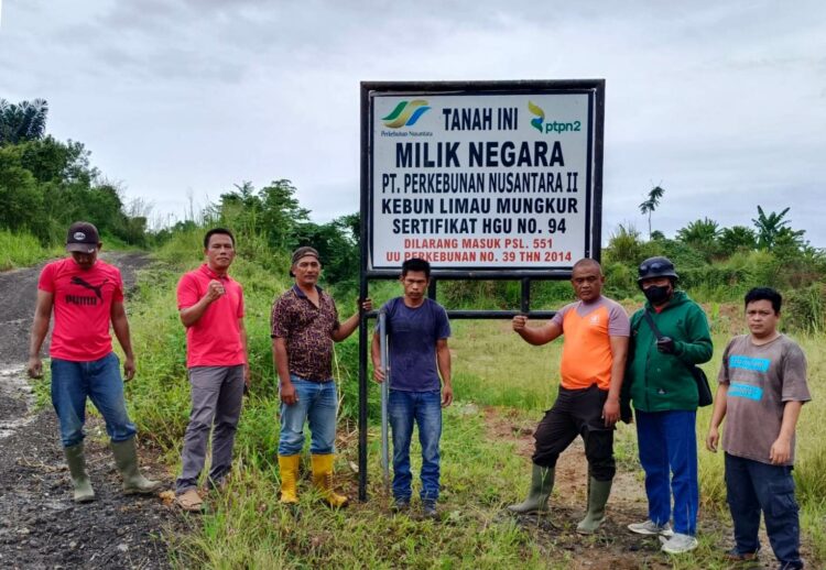 PLANG HGU : Karyawan PTPN2 Kebun Limau Mungkur berfose di jalan masuk menuju areal yang akan dibersihkan dan terdapat plang HGU milik PTPN2, baru-baru ini. (Foto.Dok/PTPN2).