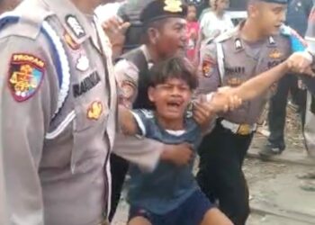 DIAMANKAN: Seorang pria diduga terlibat dalam keributan antara dua kelompok pemuda di Belawan diamankan sejumlah petugas kepolisian, Selasa (29/8/2023). (Foto Dok/Warga)