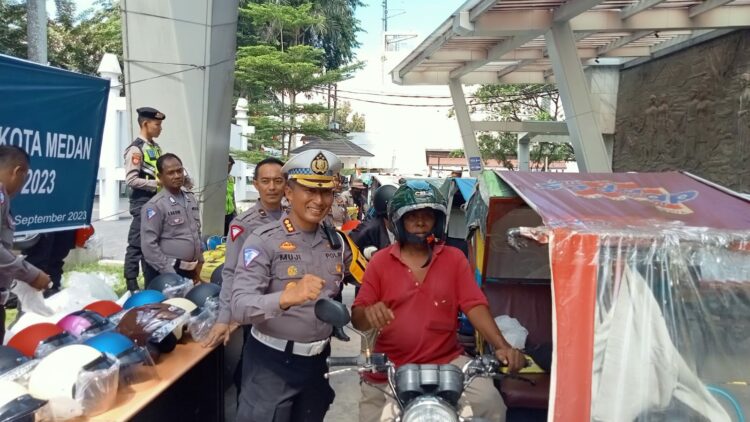 BAGI HELM: Direktur Lantas Polda Sumut, Kombes Pol Muji Ediyanto membagikan helm SNI ke abang betor, Senin (11/9/2023). (Foto Dok/ Polda Sumut)