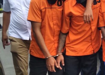 Digiring : Dua tersangka pelaku perampokan dengan kondisi mengalami luka tembak digiring Kanit Reskrim Polsek Belawan, Selasa (10/10/2023).(Foto Dok/ Polres Belawan)