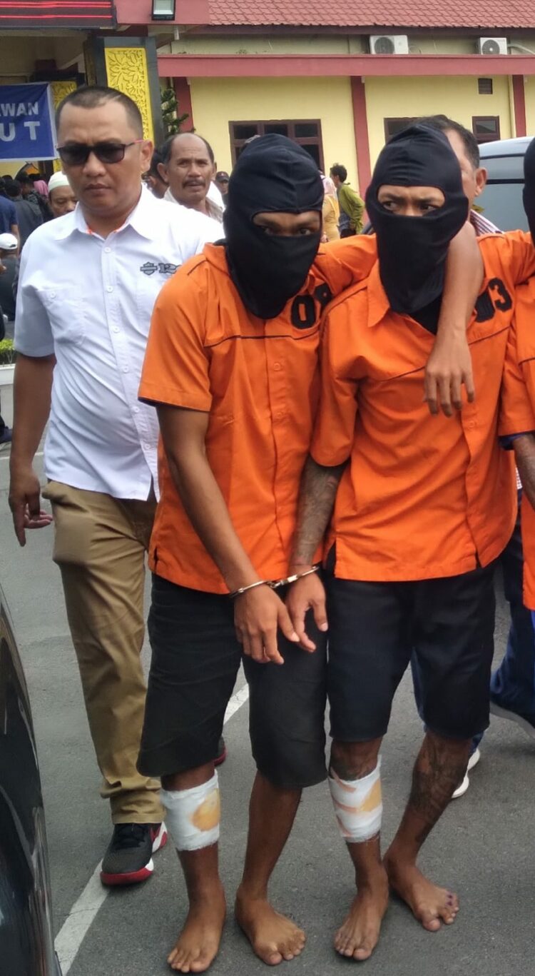 Digiring : Dua tersangka pelaku perampokan dengan kondisi mengalami luka tembak digiring Kanit Reskrim Polsek Belawan, Selasa (10/10/2023).(Foto Dok/ Polres Belawan)