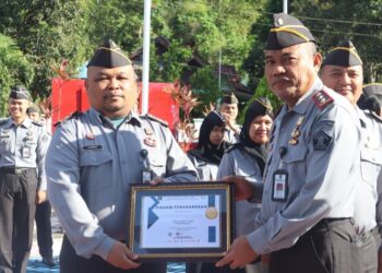 Kepala Lembaga Pemasyarakatan (Lapas) Kelas IIB Bitung Kanwil Kemenkumham Sulawesi Utara, Syukron Hamdani, menyerahkan piagam penghargaan kepada pegawai saat pelaksanaan apel pagi. Selasa (28/11/23).