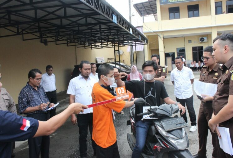 REKONSTRUKSI : ZE alias Ai (27) terduga pelaku pembunuhan terhadap pamannya Poniran (56), memeragakan adegan pada pada rekonstruksi yang digelar Satreskrim Polres Sergai disaksikan penyidik dan tim jaksa dari Kejari Sergai serta penasehat hukum teesangka, Rabu (6/12/2023). (Foto Dok/ Polres Sergai)