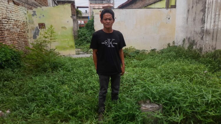 AYAH KORBAN PEMBAKARAN: Ribut Hartono, ayah dari Deni yang menjadi korban pembakaran hingga tewas karena dituduh mencuri handphone tanpa adanya bukti, saat berkunjung ke bekas rumah lamanya yang sudah rubuh Jalan Perkutut Raya Perumnas Mandala, Kecamatan Percut Sei Tuan, Deliserdang, Senin (11/12/2023).(Foto Dok/Warga)