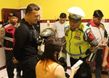 PERIKSA : Personel Polres Sergai memeriksa identitas dan barang-barang pengunjung saat merazia tempat penginapan di Seibamban, Selasa (19/12/2023) malam. (Foto Dok/Humas Polres)