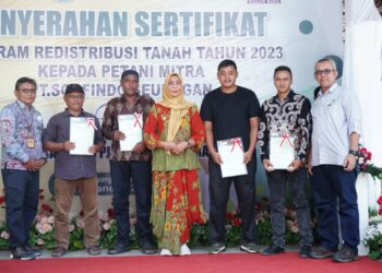 Penjabat (Pj) Bupati Nagan Raya, Fitriany Farhas AP., S.Sos., M.Si menyerahkan secara simbolis sertifikat redistribusi tanah kepada petani mitra PT Socfindo Seunagan di Desa Purwodadi, Kecamatan Kuala Pesisir, Kabupaten setempat, Jum'at (19/1/2024).