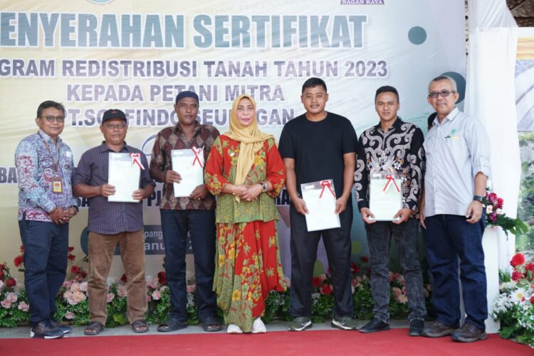 Penjabat (Pj) Bupati Nagan Raya, Fitriany Farhas AP., S.Sos., M.Si menyerahkan secara simbolis sertifikat redistribusi tanah kepada petani mitra PT Socfindo Seunagan di Desa Purwodadi, Kecamatan Kuala Pesisir, Kabupaten setempat, Jum'at (19/1/2024).