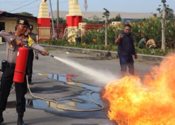 SIMULASI: Salah seorang personel Polres Pelabuhan Belawan melakukan simulasi pemadaman api yang sedang berkobar pada kegiatan sosialisasi dan pelatihan APAR, Jumat (26/1/2024).(Foto dok/Polres Belawan)