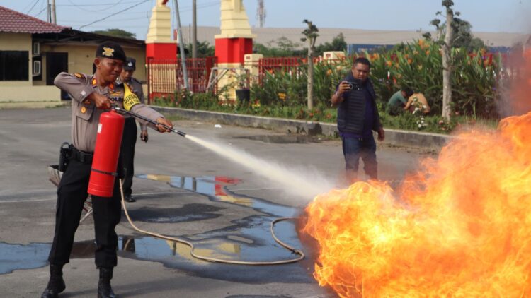 SIMULASI: Salah seorang personel Polres Pelabuhan Belawan melakukan simulasi pemadaman api yang sedang berkobar pada kegiatan sosialisasi dan pelatihan APAR, Jumat (26/1/2024).(Foto dok/Polres Belawan)