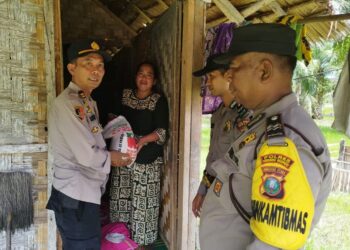 SERAHKAN BANTUAN : Kanit Samapta Polsek Tanjungberingin, Iptu Supriadi didampingi personel menyerahkan bantuan sosial bahan pangan ke warga, Sabtu (27/1/2024). (Foto Dok/Polsek Tanjungberingin)