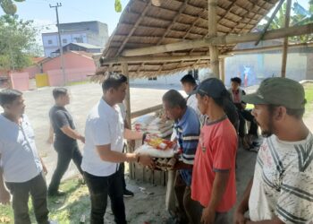 SERAHKAN BANTUAN : Kanit I Satnarkoba Polres Sergai, Ipda Anggiat Sidabutar menyerahkan paket bantuan bahan pangan ke warga nelayan di Dusun I Desa Pantaicermin Kiri, Kecamatan Pantaicermin, Rabu (31/1/2024). (Foto Dok/Humas Polres)