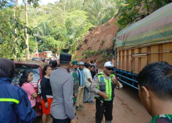 PANTAU: Personel Polisi memantau pembersihan material longsor yang menutup Jalan Lintas Tarutung-Sibolga, KM 31, tepatnya di Kecamatan Adiankoting, Kabupaten Tapanuli Utara (Taput). (Foto Dok/ Polda Sumut)