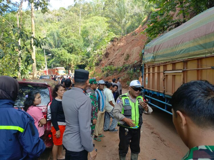 PANTAU: Personel Polisi memantau pembersihan material longsor yang menutup Jalan Lintas Tarutung-Sibolga, KM 31, tepatnya di Kecamatan Adiankoting, Kabupaten Tapanuli Utara (Taput). (Foto Dok/ Polda Sumut)