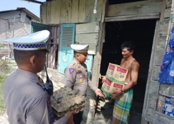 SERAHKAN BANTUAN : Kasat Lantas Polres Sergai, AKP Andita Sitepu didampungi Kbo Iptu W Saragih menyerahkan paket bantuan ke warga kurang mampu pada kegiaran Baksos Jumat Berkah, Jumat (23/2/2024). (Foto Dok/Humas Polres)