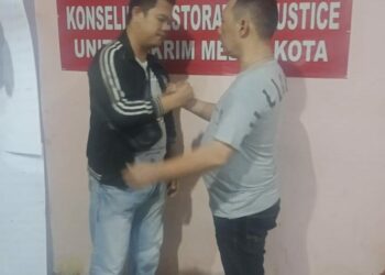 BERSALAMAN: Pelaku pemukulan, Ibrahim Maryabaya bersalaman dengan korban, Surya Yudistira di Mapolsek Medan Kota. (Foto Ist)