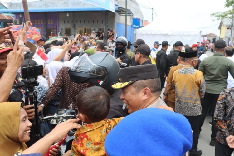 GENDONG ANAK: Kapolda Sumut, Irjen Pol Agung Setya Imam Effendi menggendong seorang anak yang antusias ingin melihat Presiden Jokowi, Kamis (14/3/2024).(Foto Dok/ Polda Sumut)