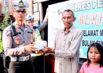 BAGI TAKJIL: Kasat Lantas Polres Pelabuhan Belawan membagikan takjil kepada salah seorang warga di Belawan, Sabtu (16/3/2024).(Foto Dok/Polres Belawan)