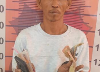 DIAMANKAN : R (40), terduga penulis Togel Sidney beserta barang bukti, diamankan di Satreskrim Polres Sergai. (Foto Dok/Humas Polres)