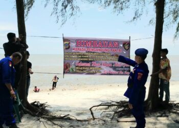 SPANDUK IMBAUAN : Personel Satpol Airud Polres Sergai memasang spanduk imbauan Kamtibmas di lokasi objek wisata pantai di Kecamatan Pantaicermin, Kamis (11/4/2024). (Foto Dok/Humas Polres)