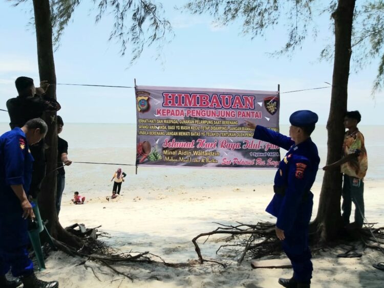 SPANDUK IMBAUAN : Personel Satpol Airud Polres Sergai memasang spanduk imbauan Kamtibmas di lokasi objek wisata pantai di Kecamatan Pantaicermin, Kamis (11/4/2024). (Foto Dok/Humas Polres)