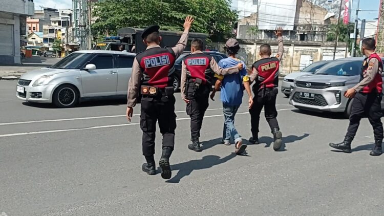 AMANKAN JUKIR: Polrestabes Medan bersama dengan Satgas gabungan mengamankan salah seorang jukir yang terjaring razia, Minggu (21/4/2024).(Foto Dok/Polrestabes)