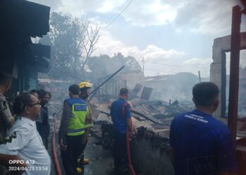 PADAMKAN API: Petugas pemadam kebakaran berusaha memadamkan api dengan menyemprotkan air di rumah permanen Asrama Kodam  I/BB Jalan Sejati Gang Tangsi Kelurahan Sidorame Barat, Kecamatan Medan Perjuangan, Selasa (23/4/2024).(Foto Dok/T77)
