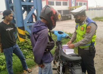 TINDAK: Personel Unit Lantas Polres Pelabuhan Belawan menindak seorang pengendara sepeda motor, yang melakukan pelanggran berlalu lintas, Kamis (2/5/2024).(Foto Dok/Polres Belawan)