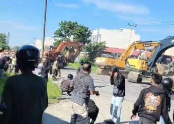 KERICUHAN: Masyarakat Kampung Kompak melempari alat berat yang akan merubuhkan bangunan mereka di lahan garapan Jalan H Anif Desa Sampali, Kecamatan Percut Sei Tuan, Deliserdang, hingga terjadi kericuhan, Kamis (11/7/2024).(Foto Dok/ warga)