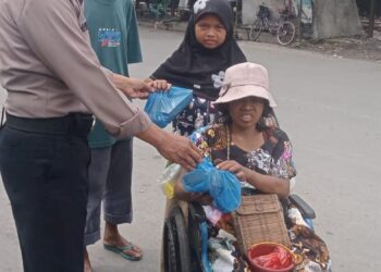 Jumat Berkah: Salah seorang personel Polsek Belawan memberikan makanan dan minuman kepada warga kurang mampu, dalam kegiatan Jumat Berkah di Belawan, Jumat (12/7/2024).(Foto Dok/Polres Belawan)