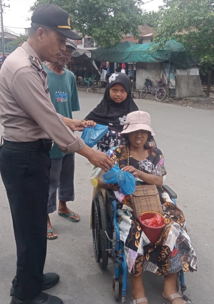 Jumat Berkah: Salah seorang personel Polsek Belawan memberikan makanan dan minuman kepada warga kurang mampu, dalam kegiatan Jumat Berkah di Belawan, Jumat (12/7/2024).(Foto Dok/Polres Belawan)